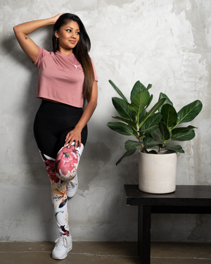 girl in high waisted leggings roses and lilies and pink crop tee posing in front of a concrete wall